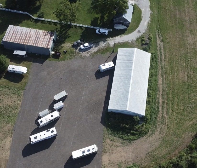 Aerial view of the Haystack Storage lot: gravel parking area with RVs and trailers, the enclosed storage building, and surrounding farmland.